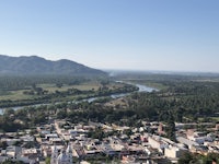 a view of a town and river with mountains in the background