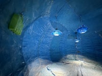the inside of an ice cave with lights hanging from the ceiling